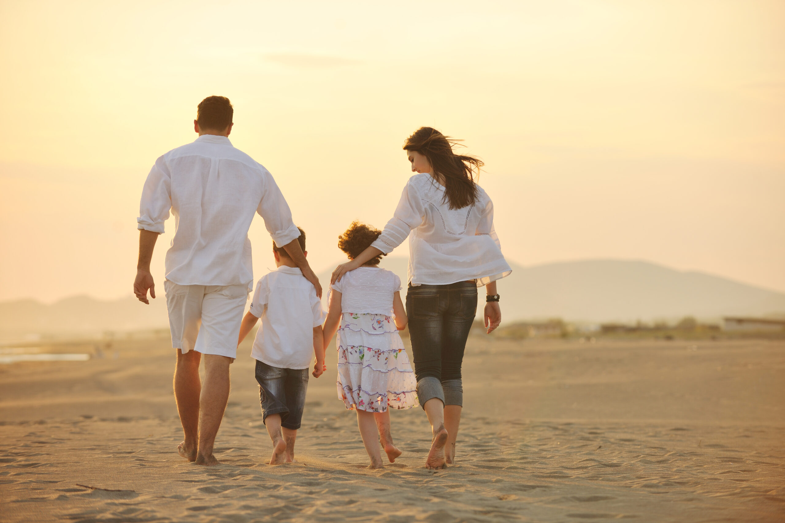 happy young family have fun on beach run and jump  at sunset